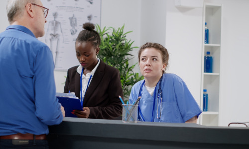 equipe-medicale-diversifiee-travaillant-a-la-reception-de-l-hopital-aidant-les-patients-avec-des-rendez-vous-de-controle-et-des-documents-de-rapport-infirmiere-et-receptionniste-assis-au-comptoir-d-inscription